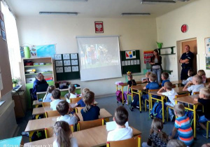 Uczniowie klas pierwszych oglądają prezentację.