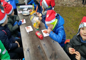 Uczniowie spożywają posiłek na rajdzie.