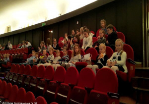 Uczniowie siedzą w teatrze.